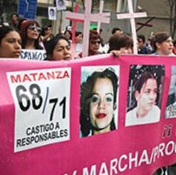 Women marching in street parade carrying crosses and pink banners